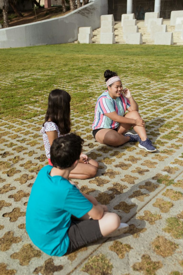Children and a counselor enjoy a sunny day outdoors at a summer camp.